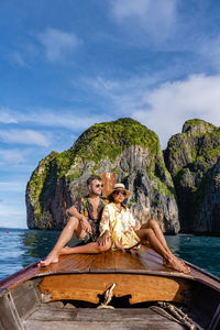 Woman sitting on rock by sea against sky