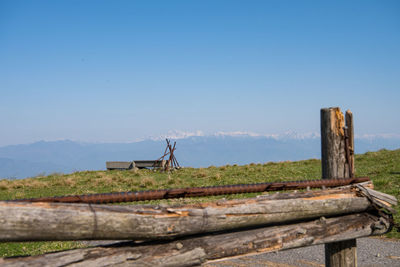 Wooden post by lake against clear blue sky