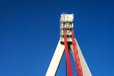 Low angle view of rollercoaster against clear blue sky