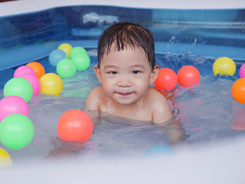 Portrait of smiling boy with ball in swimming pool