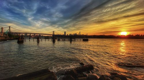 Scenic view of the east river and williamsburg bridge against sky during sunset