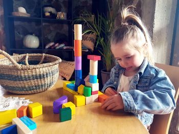 Cute girl looking away while sitting on table at home