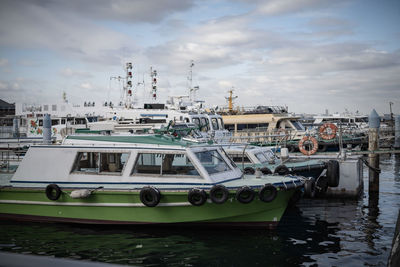 Boats moored at harbor against sky