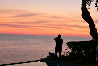 Silhouette man standing on beach against sky during sunset