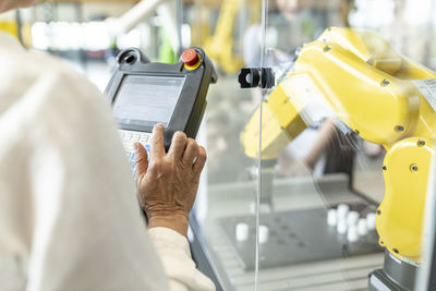 Woman in factory using control of industrial robot