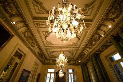 Low angle view of illuminated chandelier hanging on ceiling