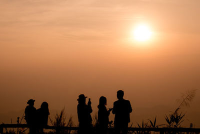 Silhouette people looking at sunset