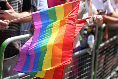 Midsection of people with rainbow flags in city