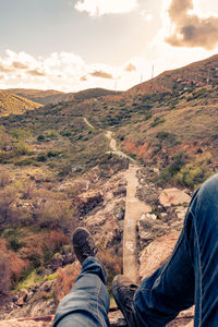 Low section of man on mountain against sky