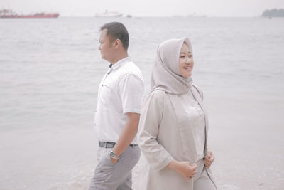 Friends standing on sea shore