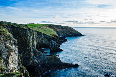 Scenic view of sea by cliff against sky