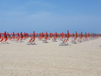 Row of chairs on beach against clear sky