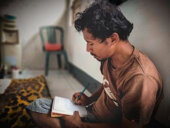 Man holding book while sitting on table at home