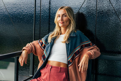 Portrait of a confident blonde woman standing against a wall. person