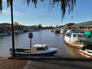 Boats moored at harbor against buildings in city