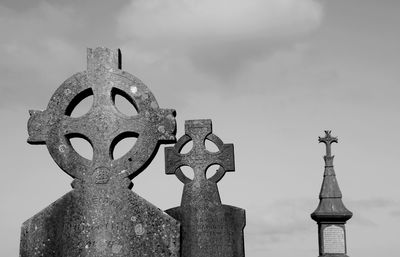 Low angle black and white view of irish cross headstone against sky