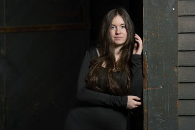 Portrait of young woman standing against wall