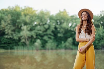 Portrait of young woman standing against lake