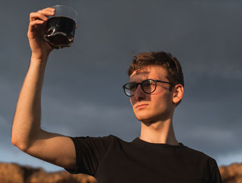 Portrait of young man drinking glasses outdoors