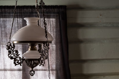 Close-up of lamp hanging against window at home