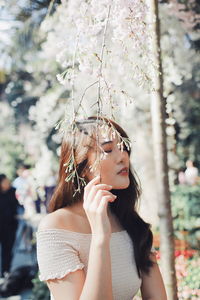 Young woman with eyes closed standing by plants in park