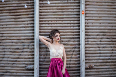 Portrait of a young woman standing against brick wall