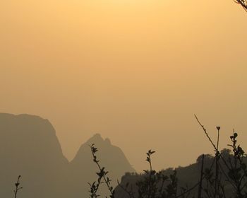 Scenic view of silhouette mountains against orange sky