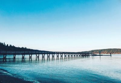 Pier in sea against blue sky