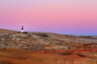 Lighthouse on dramatic landscape against clear sky during sunset