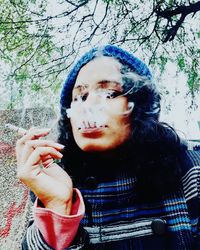 Portrait of young woman smoking outdoors