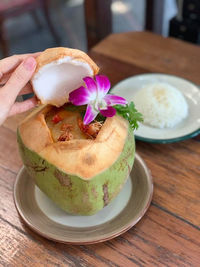 Close-up of hand holding ice cream in plate on table