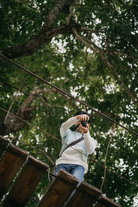 Low angle view of man photographing in forest