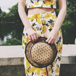 Mid section of a woman holding hat