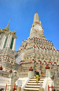 Woman going up to the central spire called phraprang of wat arun temple, thailand