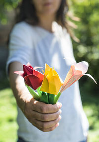 Midsection of woman holding origami flowers while standing outdoors