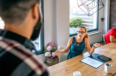 Surprised woman arguing with colleague for problems in coworking