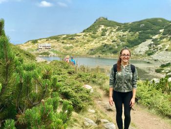 Portrait of smiling young woman standing against lake 