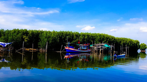 Fishing boat moored in lake against sky