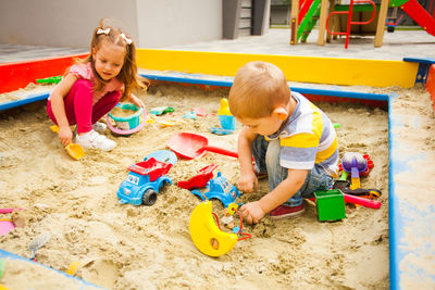 High angle view of siblings playing with toy on sand