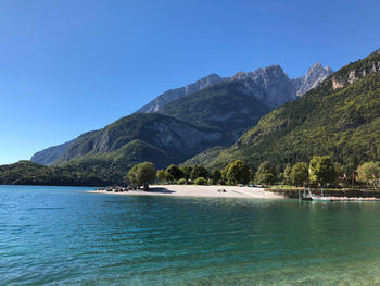 Scenic view of sea and mountains against clear blue sky