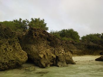 Rock formation by sea against sky