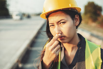 Portrait of female engineer inhaling inhaler while standing at construction site