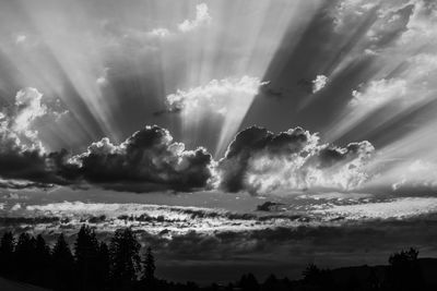 Low angle view of sunlight streaming through clouds