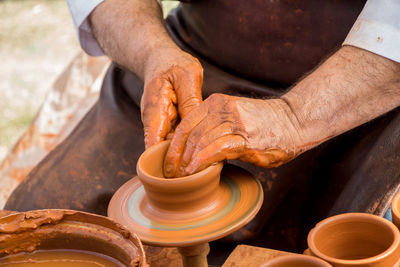 Midsection of potter making pot on pottery wheel