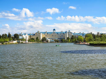 View of buildings by river against cloudy sky
