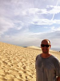 Portrait of man standing at desert against cloudy sky