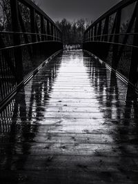 Wet footbridge against trees during rainy season