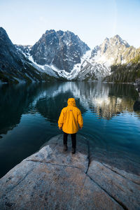 Rear view of person on lake by snowcapped mountain against sky