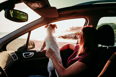 Woman with dog sitting in car