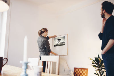 Man looking at woman holding painting frame at home